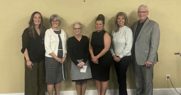 A group of five women and one man are standing together for a group photo.