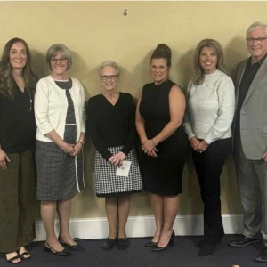 A group of five women and one man are standing together for a group photo.