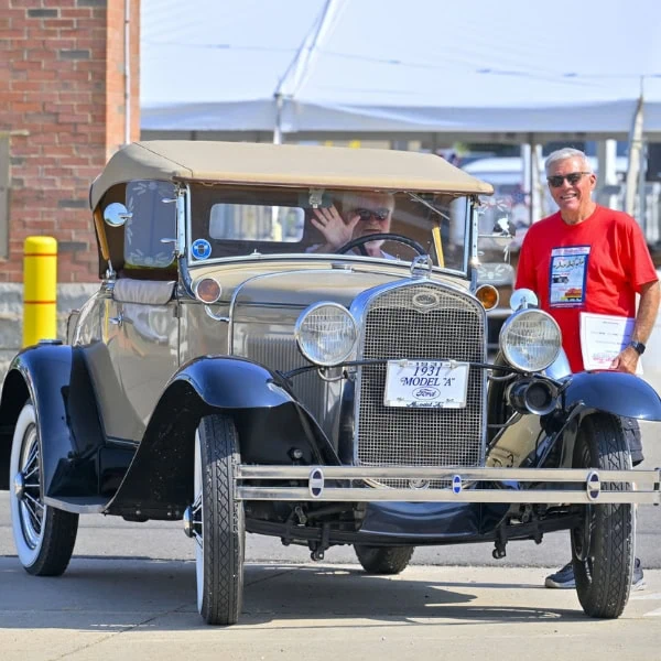 Two men posing with a vintage car.