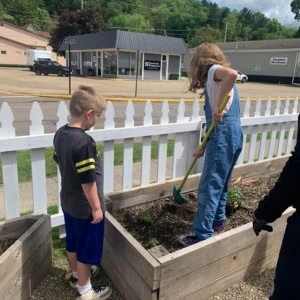 Two children are helping tend plants in a planter.