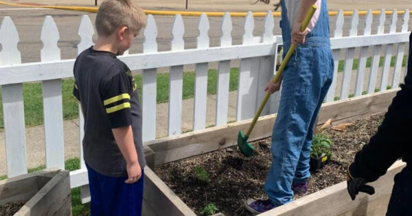 Two children are helping tend plants in a planter.