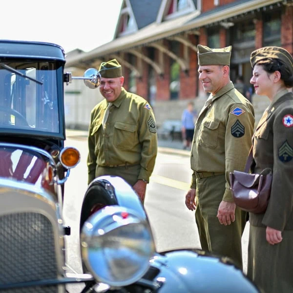 WWII Reenactors posing by a vintage car
